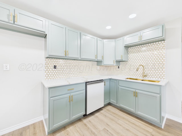 kitchen with backsplash, white dishwasher, light wood-style floors, and a sink