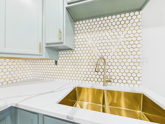 kitchen featuring light stone countertops, a sink, and tasteful backsplash