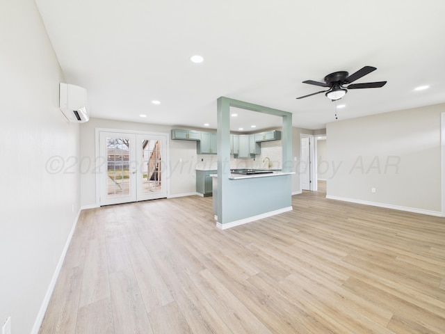 unfurnished living room with french doors, light wood-type flooring, baseboards, an AC wall unit, and recessed lighting