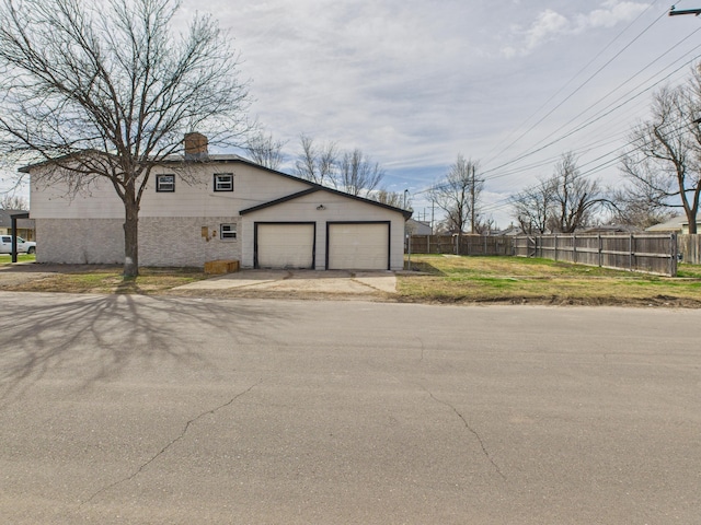 exterior space with a yard, a chimney, fence, and driveway