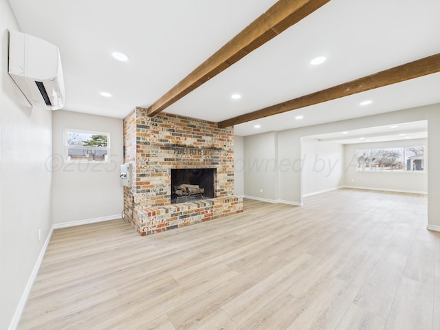unfurnished living room featuring a wall unit AC, baseboards, beam ceiling, light wood finished floors, and a brick fireplace