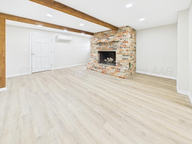 unfurnished living room with an AC wall unit, baseboards, and wood finished floors