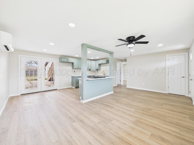 unfurnished living room featuring baseboards, light wood-type flooring, and an AC wall unit