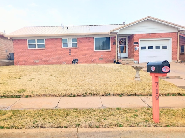 ranch-style home featuring cooling unit, brick siding, metal roof, and an attached garage