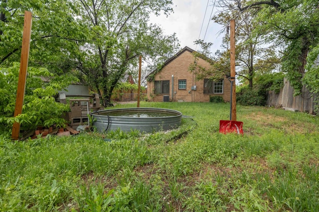 view of yard featuring an outdoor hot tub and fence