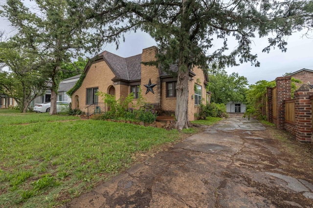 view of side of home featuring a yard, brick siding, and roof with shingles