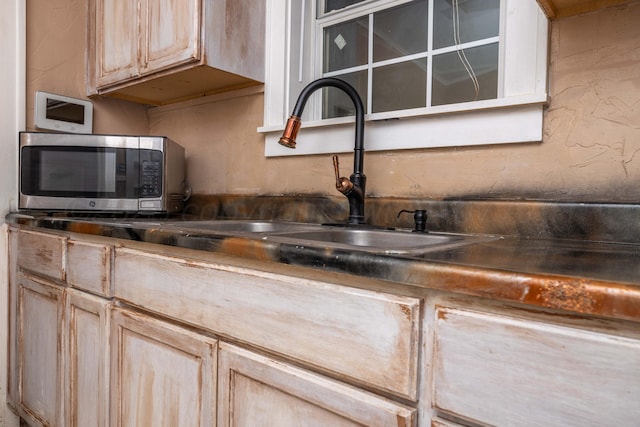kitchen with a sink, stainless steel microwave, light brown cabinetry, and tasteful backsplash