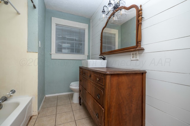 full bath featuring a tub, tile patterned flooring, baseboards, vanity, and toilet