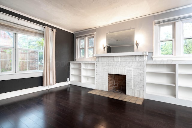 unfurnished living room featuring a brick fireplace, ornamental molding, and hardwood / wood-style flooring