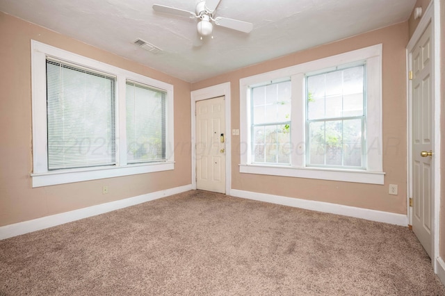 empty room featuring plenty of natural light, carpet flooring, baseboards, and visible vents