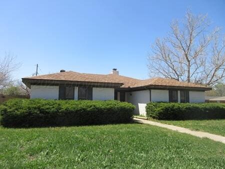 single story home with a chimney, a garage, and a front yard