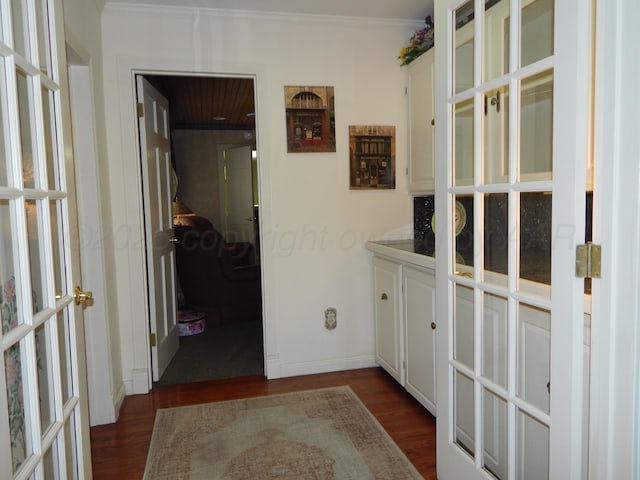 corridor with french doors, ornamental molding, dark wood finished floors, and baseboards