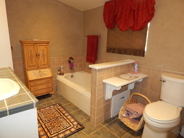 bathroom with tile patterned floors, toilet, a bath, and tile walls