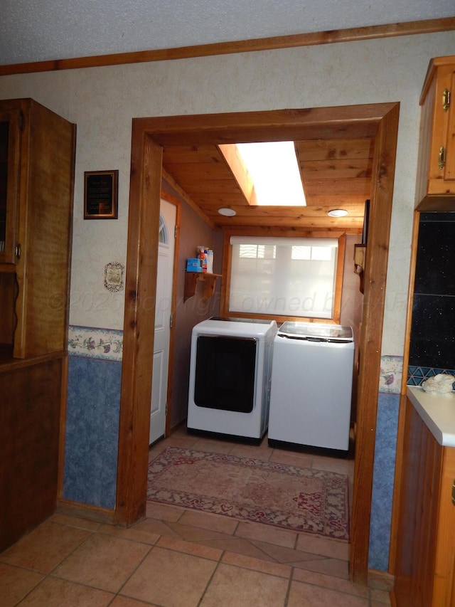 washroom featuring crown molding, a skylight, washing machine and clothes dryer, and laundry area