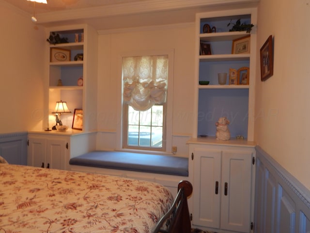 bedroom featuring a decorative wall and a wainscoted wall