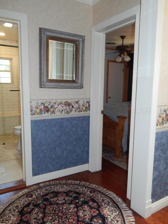full bath with baseboards, toilet, wood finished floors, a ceiling fan, and tiled shower