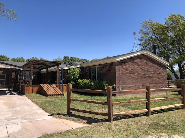 exterior space with brick siding, fence, and a front yard