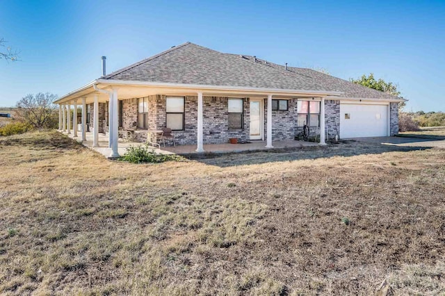 rear view of property with a garage and a yard