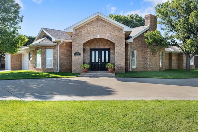 1918 Arroya Rd, Dalhart, TX 79022 - view of front facade featuring brick siding, a chimney, a front lawn, and french doors