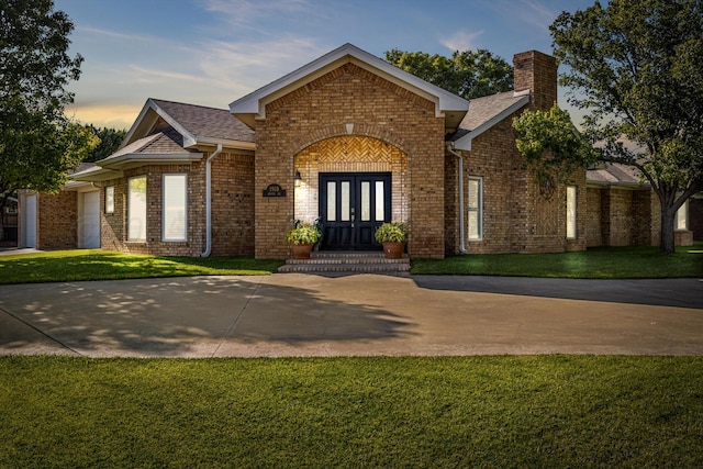 1918 Arroya Rd, Dalhart, TX 79022 - view of front facade with an attached garage, brick siding, concrete driveway, french doors, and a chimney