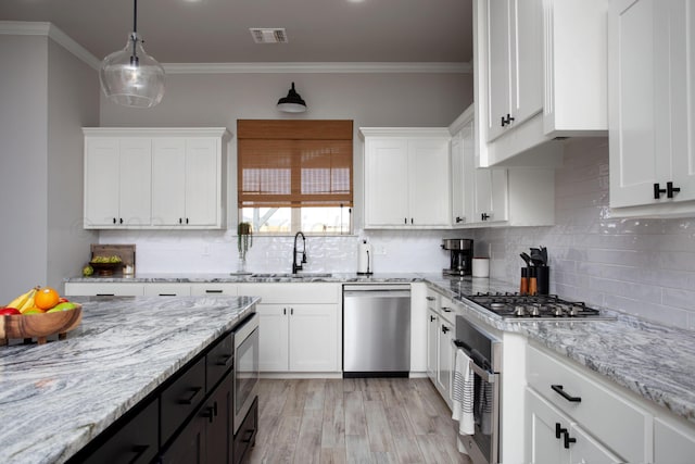 kitchen with decorative light fixtures, white cabinets, appliances with stainless steel finishes, and sink