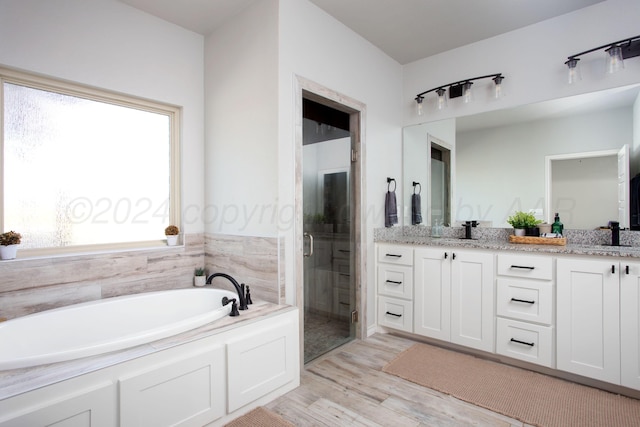 bathroom with hardwood / wood-style floors, vanity, and shower with separate bathtub