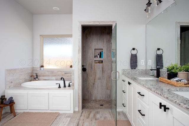 bathroom featuring vanity, hardwood / wood-style floors, and plus walk in shower