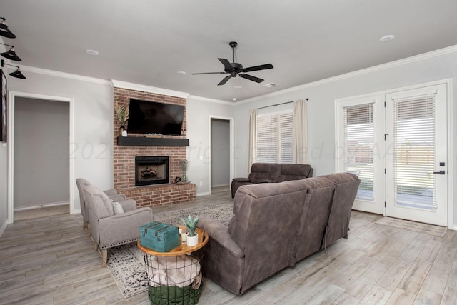 living room featuring a brick fireplace, light wood-type flooring, ceiling fan, and ornamental molding