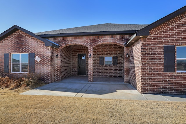 property entrance featuring a lawn and a patio