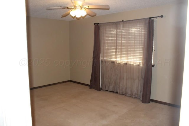 spare room featuring light carpet, baseboards, a ceiling fan, and a textured ceiling