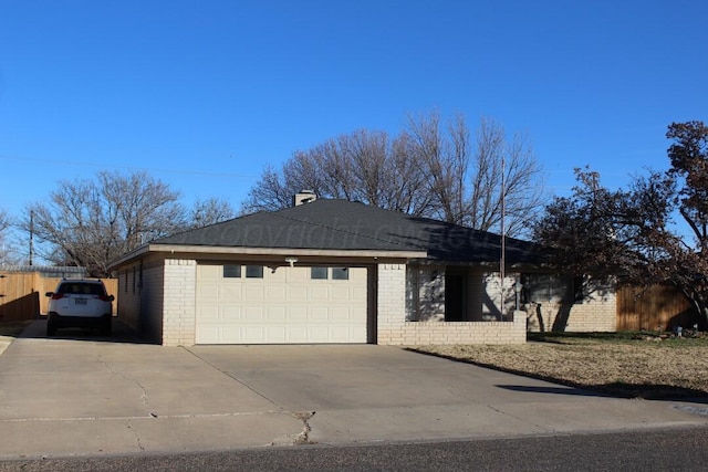 exterior space featuring concrete driveway, brick siding, an attached garage, and fence