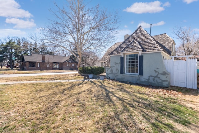 exterior space featuring a yard, a chimney, and stucco siding