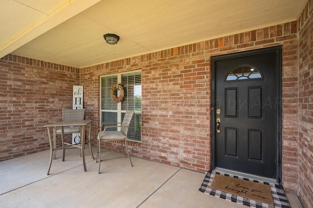 property entrance featuring brick siding and a porch