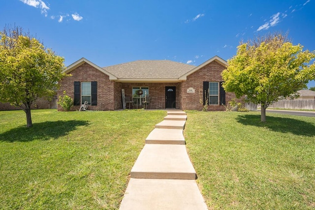 single story home featuring a shingled roof, fence, a front lawn, and brick siding