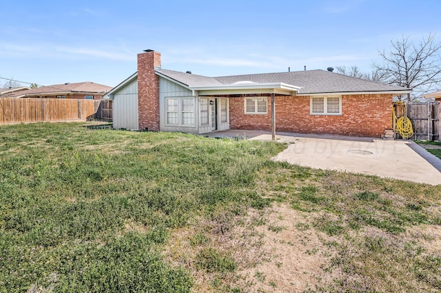 back of house with a fenced backyard, a lawn, a chimney, and a patio area