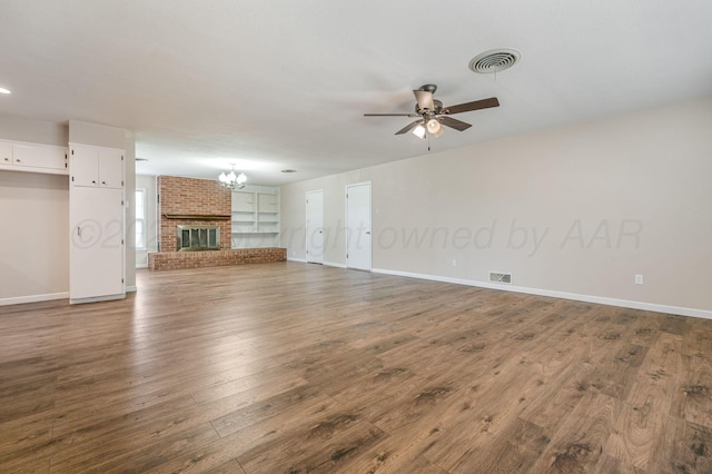 unfurnished living room featuring dark wood-style floors, visible vents, baseboards, and ceiling fan with notable chandelier