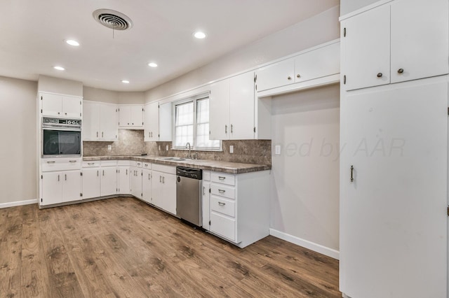 kitchen with stainless steel appliances, backsplash, a sink, visible vents, and white cabinets