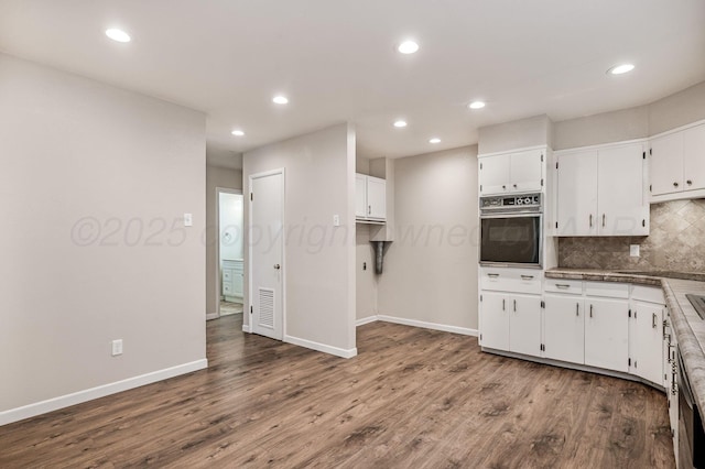 kitchen with white cabinetry, dark wood-style flooring, stainless steel oven, and decorative backsplash