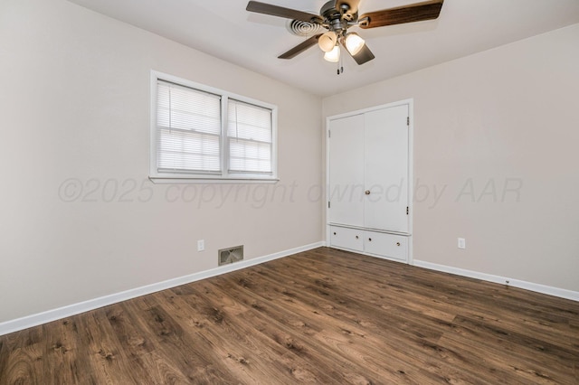 unfurnished room with baseboards, visible vents, ceiling fan, and dark wood-style flooring