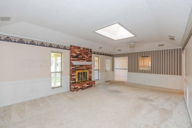unfurnished living room featuring lofted ceiling, a skylight, a textured ceiling, a ceiling fan, and carpet