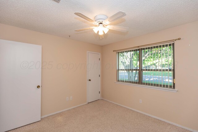 empty room featuring carpet flooring, a ceiling fan, a textured ceiling, and baseboards