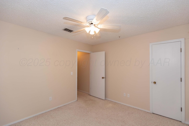 unfurnished bedroom featuring light colored carpet, baseboards, a ceiling fan, and a textured ceiling