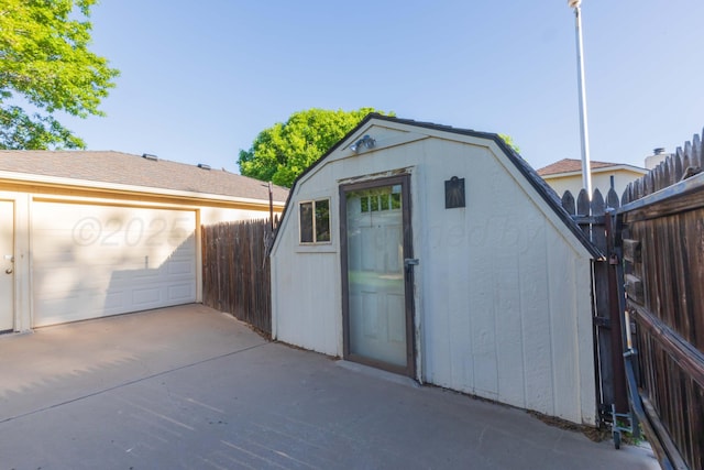 view of shed with fence and a garage