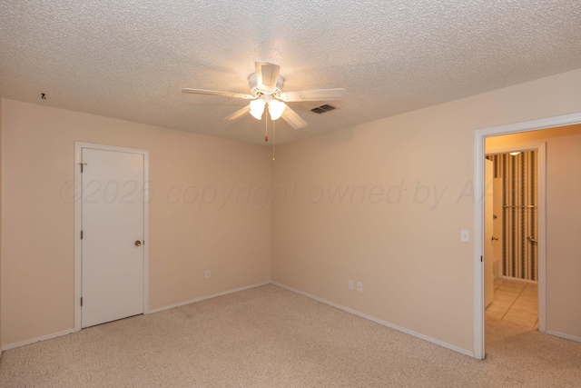 spare room featuring ceiling fan, light carpet, a textured ceiling, and baseboards