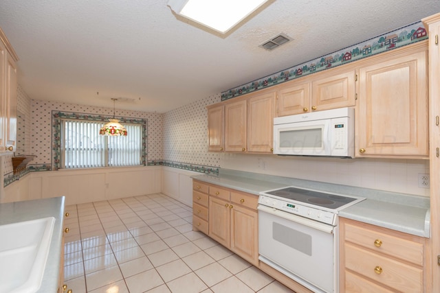 kitchen featuring white appliances, wallpapered walls, light brown cabinetry, light countertops, and a textured ceiling