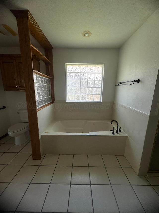 bathroom with a bathing tub, tile patterned flooring, and toilet