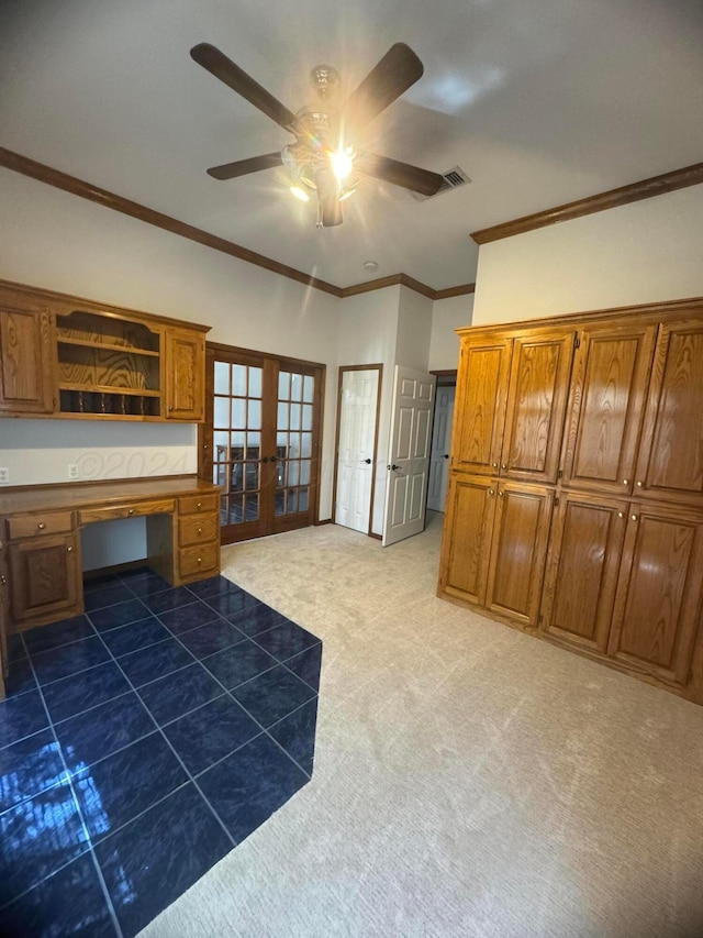 kitchen with french doors, dark carpet, ornamental molding, ceiling fan, and built in desk