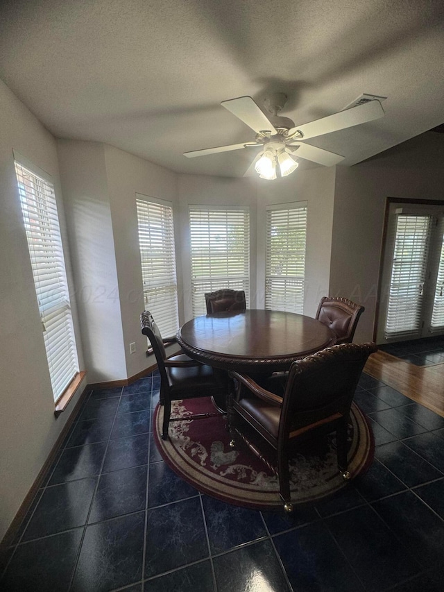 dining space featuring dark tile patterned flooring, plenty of natural light, ceiling fan, and a textured ceiling