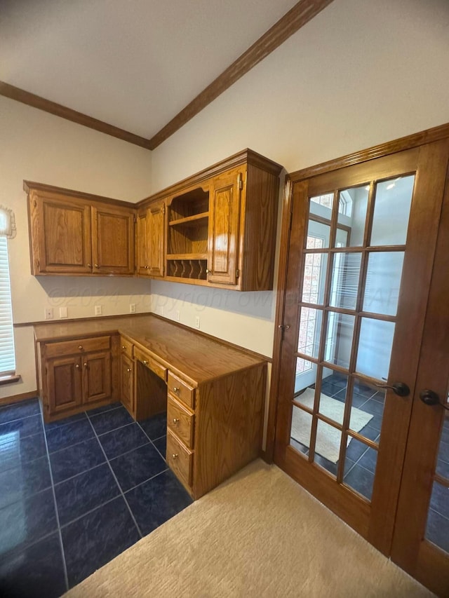 kitchen featuring built in desk, dark tile patterned flooring, and crown molding