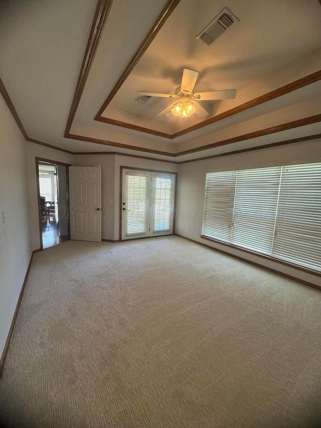 unfurnished room with carpet, a tray ceiling, plenty of natural light, and ceiling fan